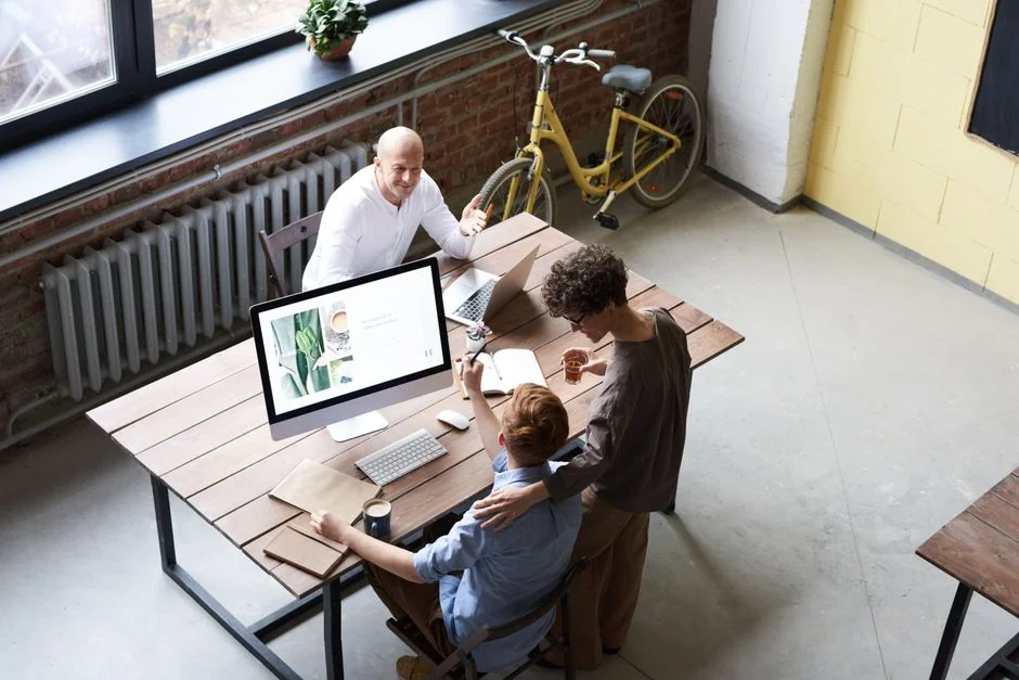 Ordinateur portable ouvert affichant l’écran d’un site web sur une table en bois, dans un décor de terrasse extérieure.